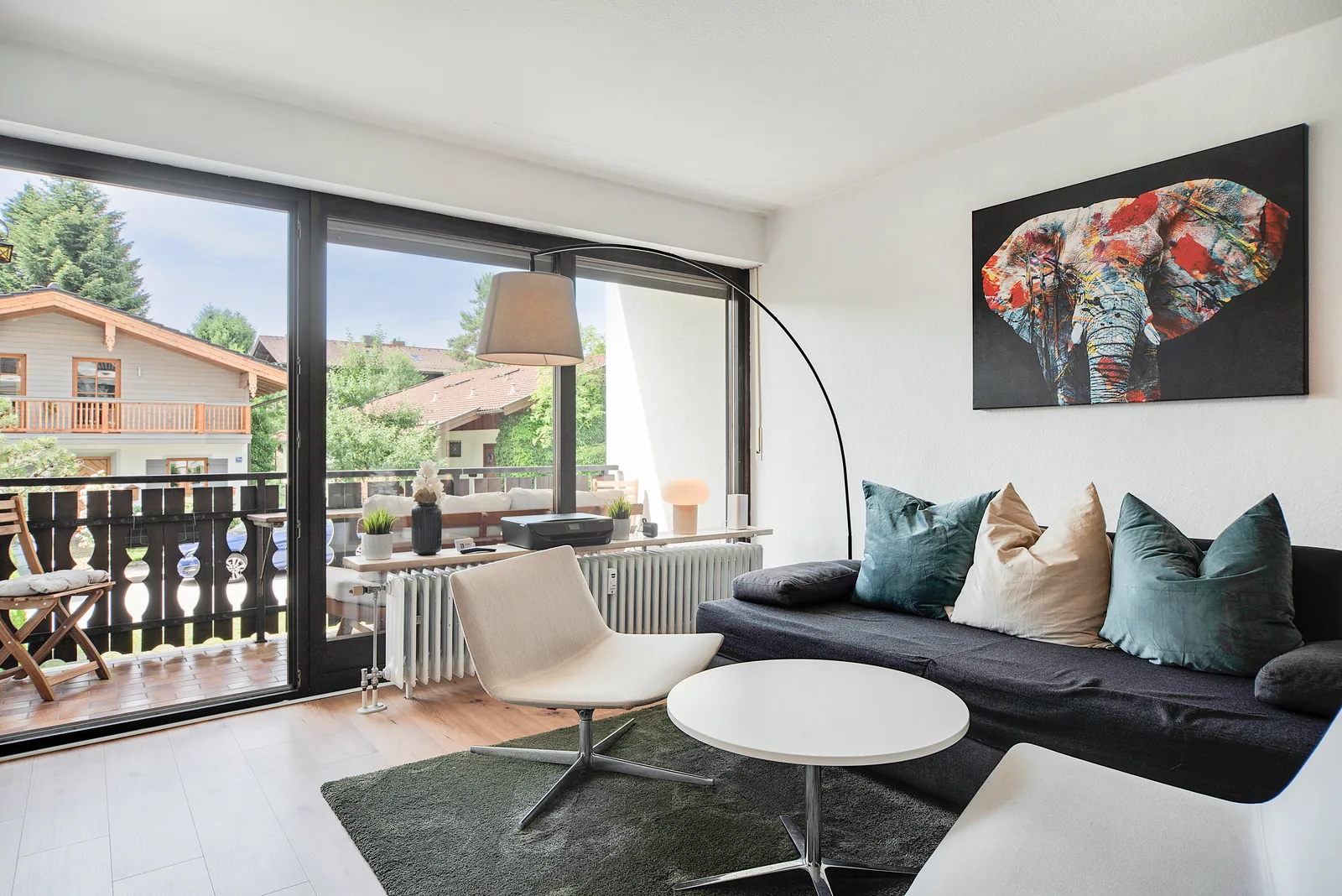 Wohnzimmer der staypfl Ferienwohnung Chiemsee in Seebruck mit Sofa, Sessel und Balkonzugang