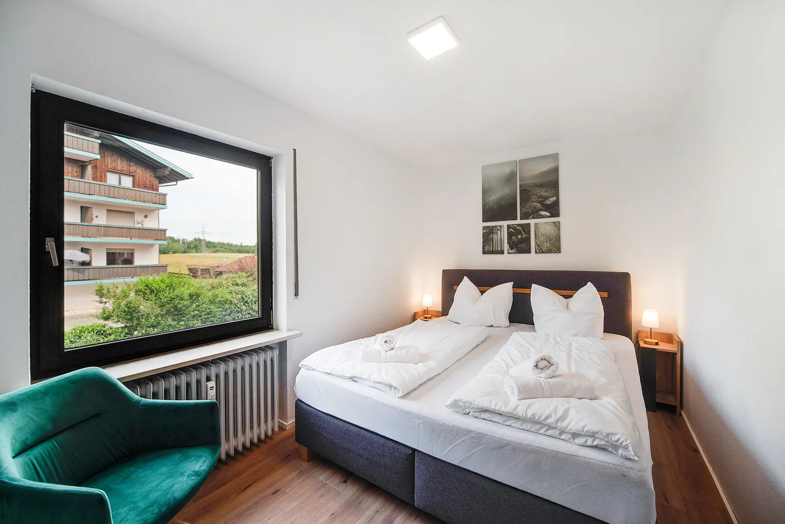 Schlafzimmer der staypfl Ferienwohnung Chiemsee in Seebruck mit Doppelbett, grünem Sessel und Fenster
