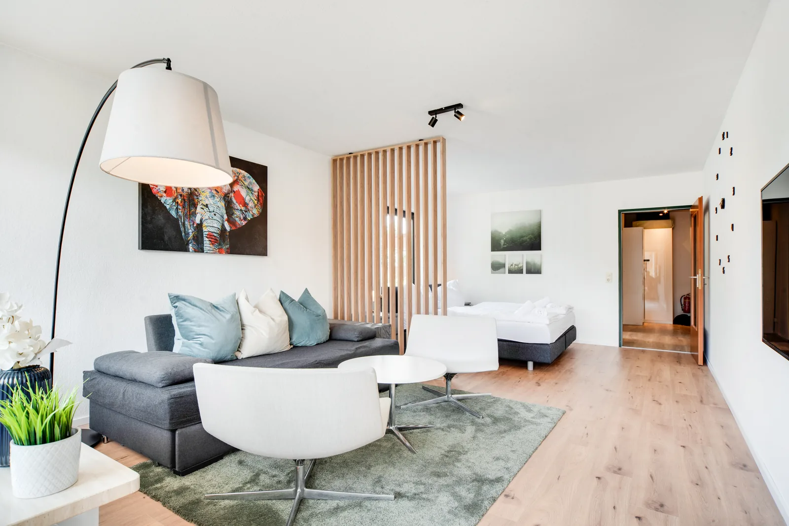 Wohnzimmer mit Sofa, Esstisch und Schlafbereich der staypfl Ferienwohnung Chiemsee