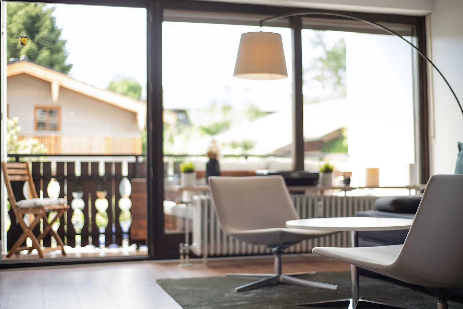 Wohnbereich der staypfl Ferienwohnung Chiemsee mit Esstisch, Sesseln und Blick zum Balkon